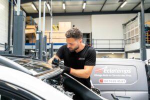 Technicien Éclatemps effectuant le remplacement d'un pare-brise dans un garage automobile.